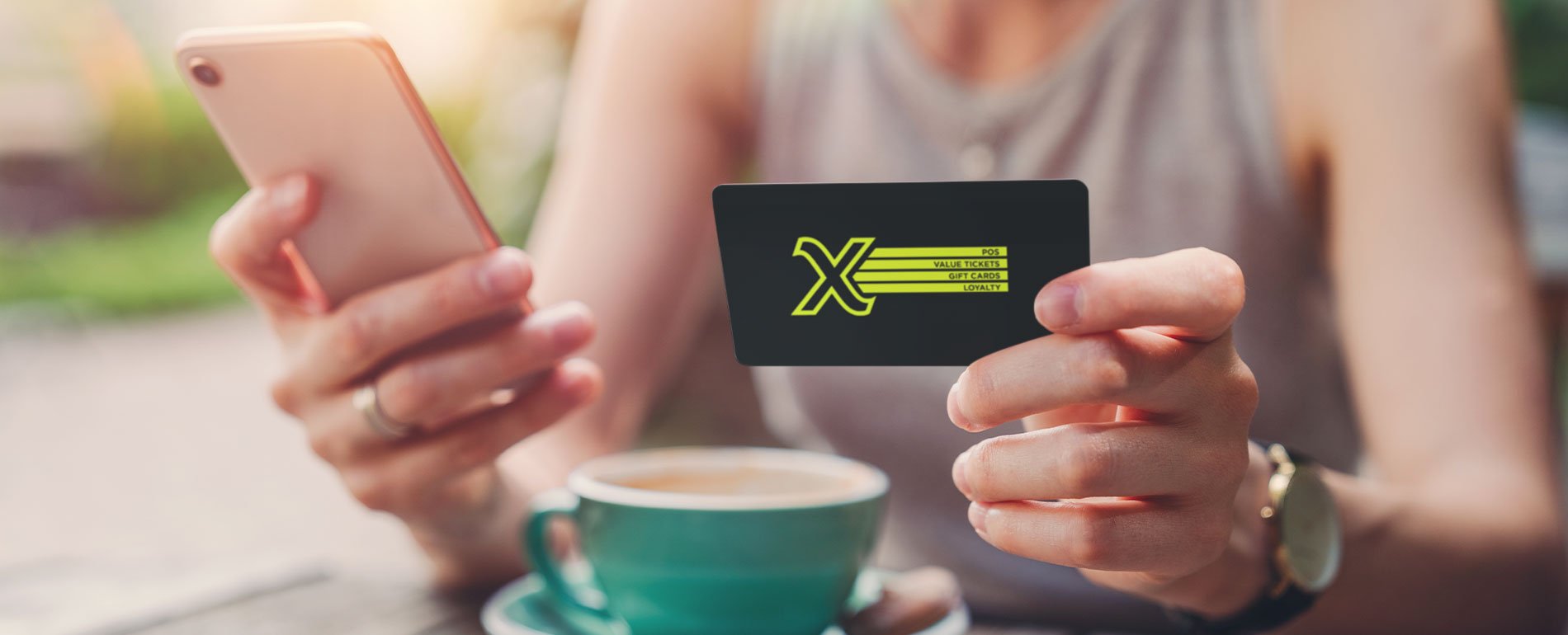 Woman enjoying a coffee while holding a Givex gift card and cell phone