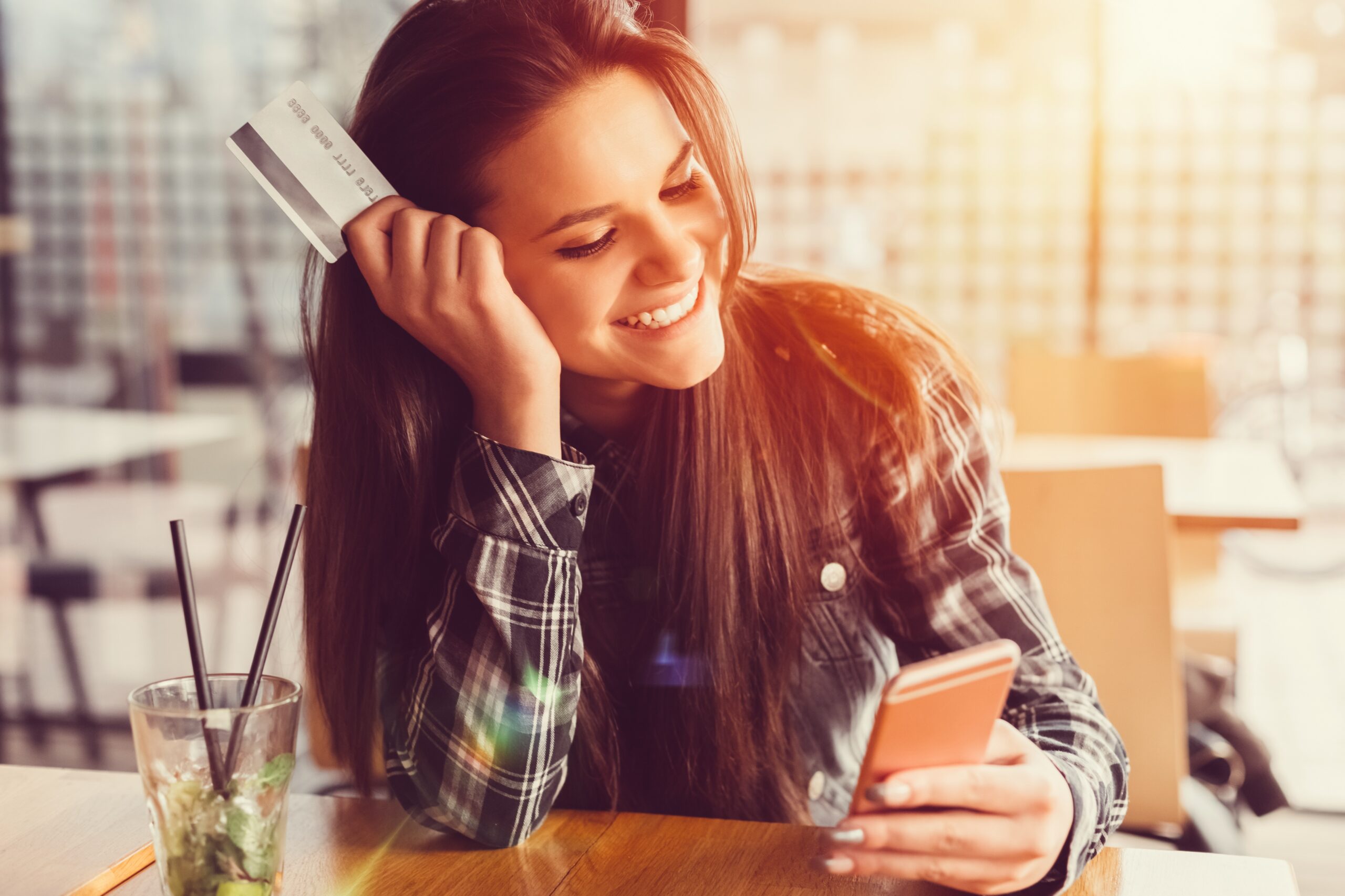 Girl-holding-credit-card-and-texting-516654892_5584x3722