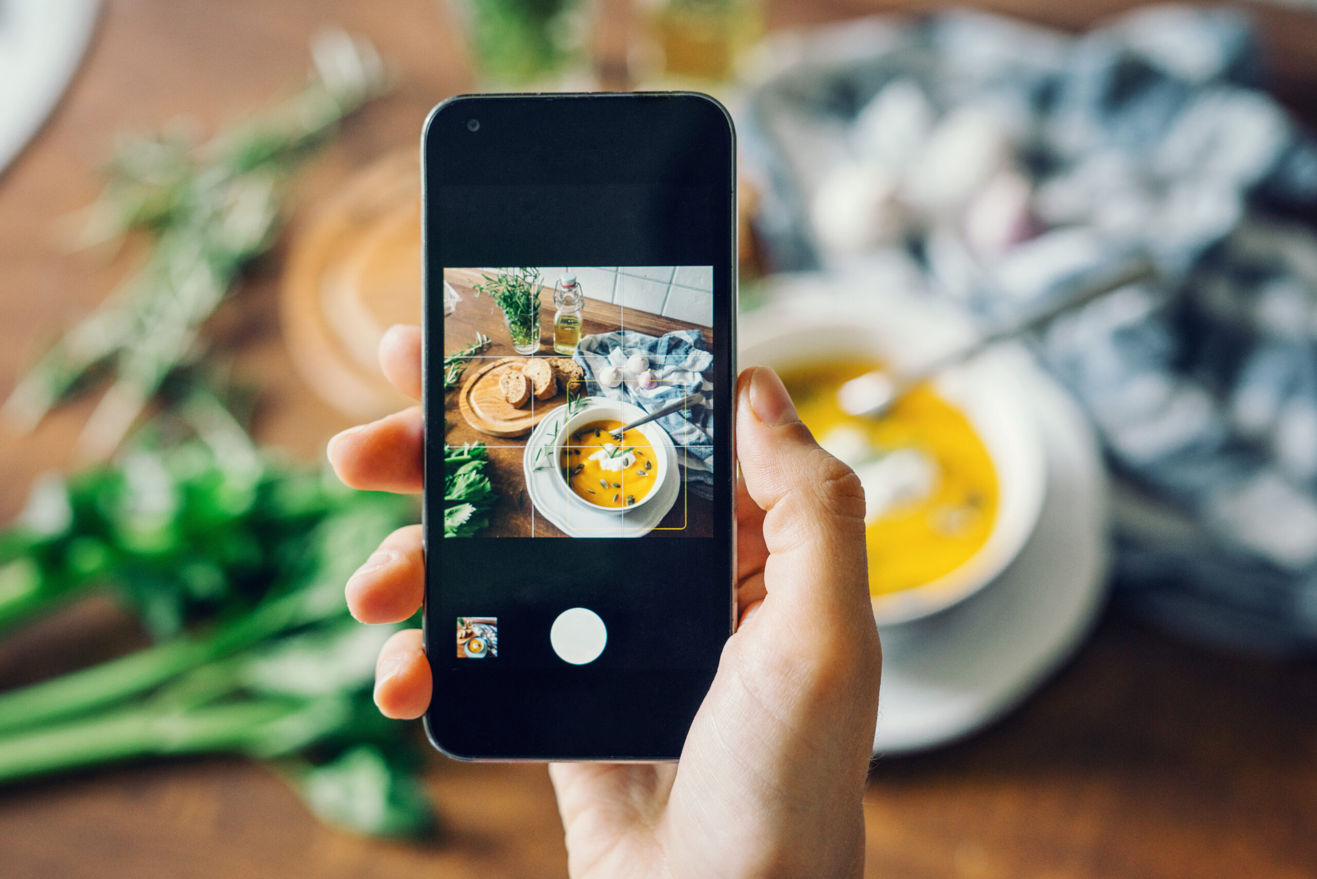 Woman-taking-photo-of-pumpkin-soup-with-smartphone-624718052_7360x4912